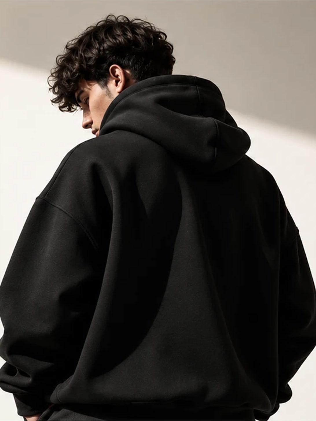 Modèle de dos portant un hoodie noir, photographié en studio
